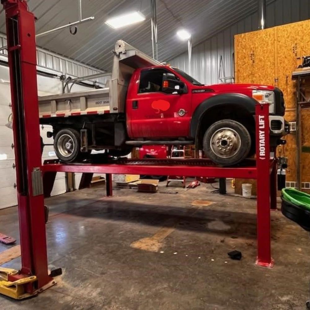 A dump truck raised on a heavy-duty four-post lift